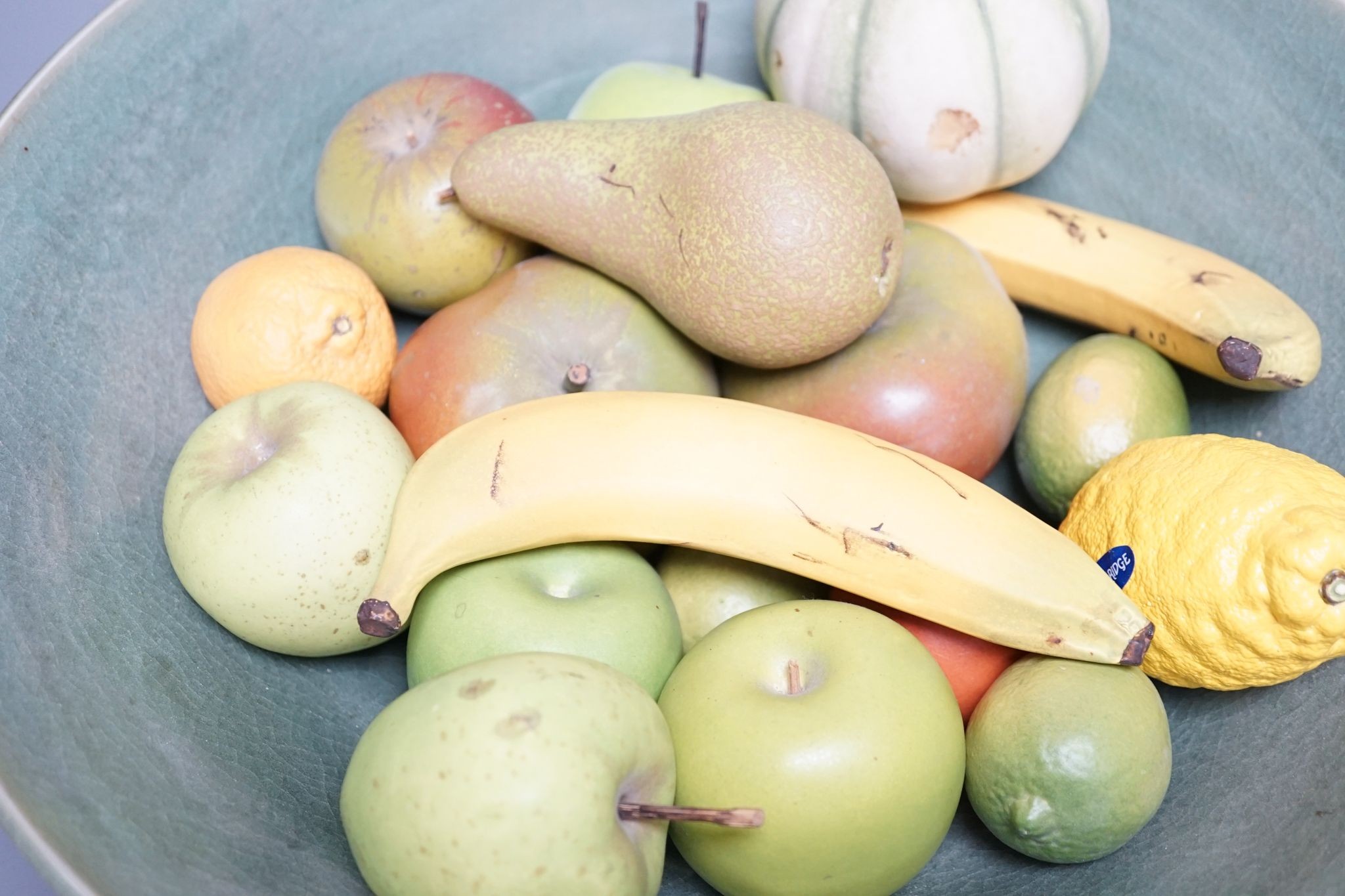 A collection of vintage Penkridge ceramic fruit including a pomegranate, melon, two bananas, limes, lemon, pear etc (18 items) in a green ceramic bowl, 42cm diameter